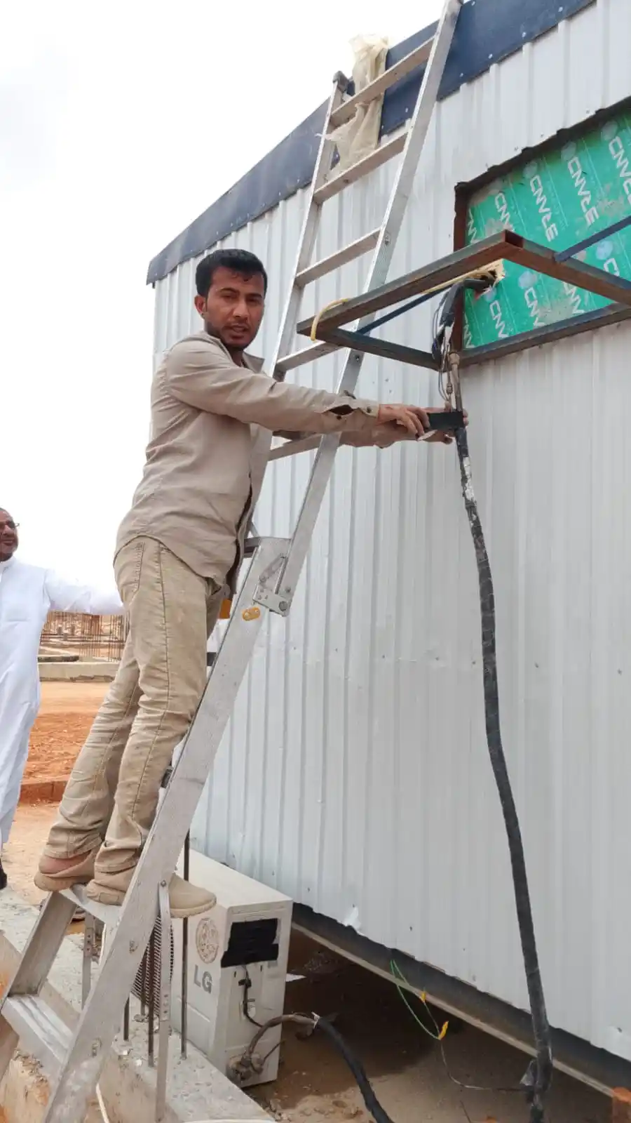 فني مكيفات يعمل على درج في مبنى رسمي بالرياض